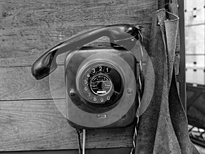 Vintage rotary dial telephone on wooden panel, monochrome image