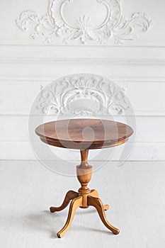 Vintage round coffee table in the Rococo style with wood carvings in a luxurious interior with stucco. Selective focus