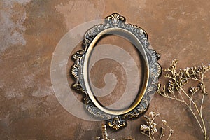 Vintage round picture frame mockup. Empty photo frame and twigs of dried flowers on decorative brown backdrop.
