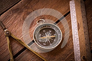 Vintage rule, drawing and navigational Compass on a rustic wooden board