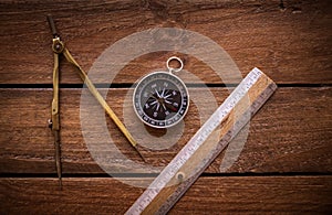 Vintage rule, drawing and navigational Compass on a rustic wooden board