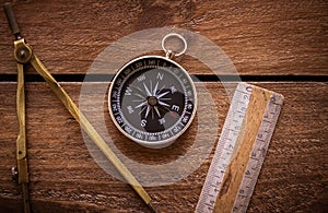 Vintage rule, drawing and navigational Compass on a rustic wooden board