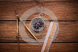 Vintage rule, drawing and navigational Compass on a rustic wooden board