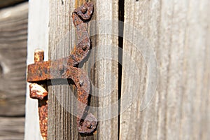 Vintage rusted metal door hinge over the weathered wooden wall.