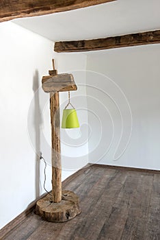 Vintage rustic lamp made of old wooden beams and stump base against white interior in  a village house