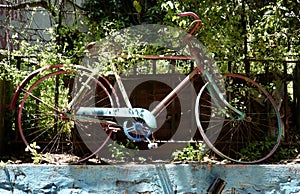 Vintage rustic pushbike on a blue wall in the sunshine.