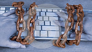 Vintage rusty chains on hands and computer keyboard