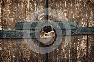 Vintage rusty padlock on old weathered wooden gates