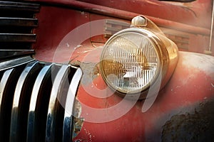 Vintage rusty red truck car with a new headlight in the sunshine