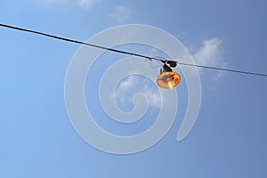 Vintage rusty street light lit on the wire on day photo