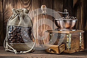 Vintage sack with coffee beans and wooden mill on wood background