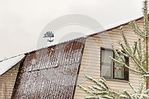 Vintage sail ship weathervane on roof in snowy day in countryside