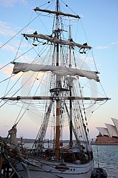 Furl the sails on sailing ship by dusk in harbor city Sydney