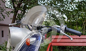 Vintage scooter or mini motorcycle stands outdoors. A popular form of transport. The steering wheel of an old blue moped with a