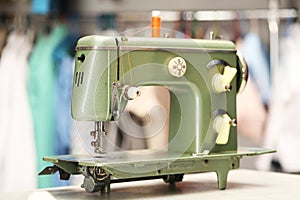 Vintage sewing machine with thread on white table in workshop, closeup