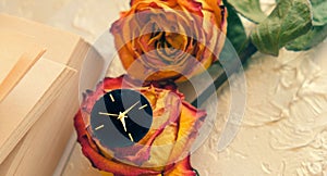 Vintage shabby black and golden watch, book and two dried red and yellow roses on  in the style of Provence. Toned and haze effect