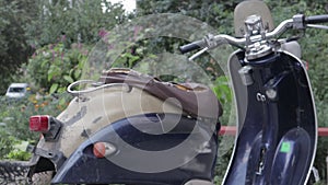 Vintage shabby scooter or mini motorcycle stands outdoors. Popular mode of transport. The steering wheel of an old blue moped with
