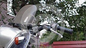 Vintage shabby scooter or mini motorcycle stands outdoors. Popular mode of transport. The steering wheel of an old blue moped with