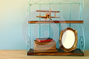 Vintage shelf with old wooden plane toy, books and blank photo frame