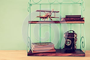 Vintage shelf with old wooden plane toy, books and decorative camera.