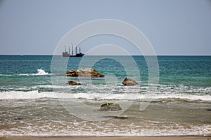 Vintage ship sailing in the distance. Black Beach, Praia Preta, Brazil. photo