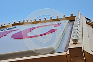 Vintage Sign Detail with Light Bulbs and Red Letter C Against Blue Sky