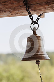 Vintage signal cast bell on the tower of a medieval outpost, vertical photo, selective focus.