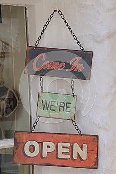 Vintage signpost, come in we`re open in one of the streets in the village Polperro in England in the summer.