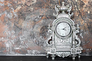 Vintage silver clock on the mantelpiece in the interior