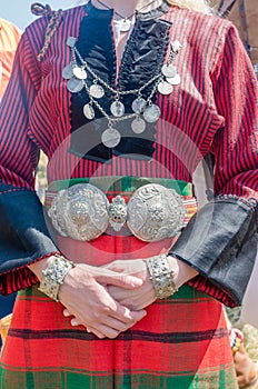 Vintage silver jewelry. Traditional women`s clothing. A young woman in Bulgarian folk costume. Silver ornaments, red robe and