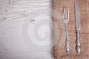 Vintage silver tableware knife and fork is on napkin, on an old