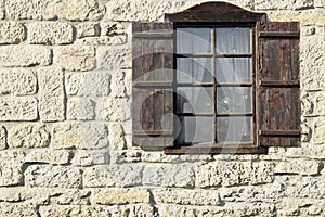 Vintage Single Window with Wooden Shutters on Natural Stone Wal