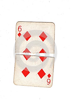 A vintage six of diamonds playing card torn in half.