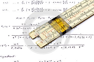 vintage slide rule being used for calculation. top view with some calculations on paper