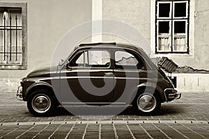 Vintage small Italian made 500 cc car in side view. grunge stucco elevation background