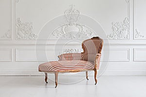 Vintage sofa with wood carvings in a luxurious light interior with stucco on the walls. Selective focus