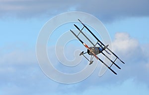 Vintage Sopwith Triplane in flight blue sky and clouds view from front