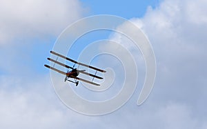 Vintage Sopwith Triplane in flight blue sky and clouds view from front