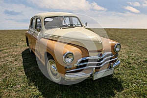 Vintage soviet car Pobeda on a field with green grass