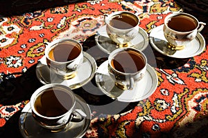 Vintage soviet porcelain cups of tea with saucers on turkish carpet, traditional tea ceremony, sunlight