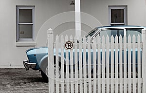 Vintage spirts car parked behind white fence; retro mood