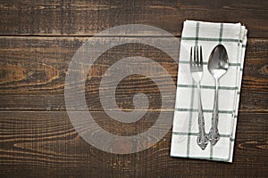 Vintage spoons and fork with napery on wooden background.