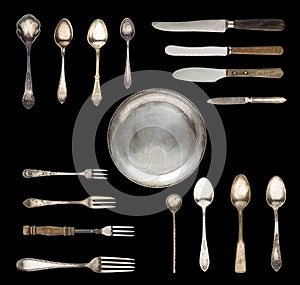 Vintage spoons, knives, forks and a plate isolated on a white background.