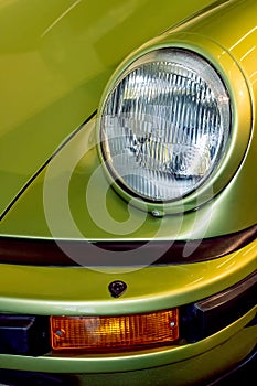 Vintage sports car headlight. Lime green motor vehicle close-up