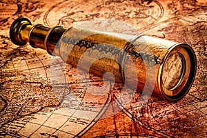 Vintage spyglass lies on an ancient world map photo