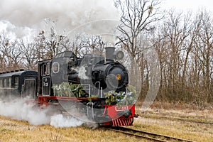 A vintage steam locomotive with old carriages runs along the rails. View of an approaching classic locomotive with the Ukrainian