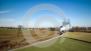 Vintage steam locomotive traveling along a set of railroad tracks cutting through a green meadow