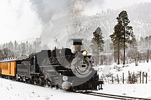 Vintage Steam Train Billowing Smoke in the Snow as it Moves Through the Mountains