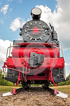 Vintage steam train on the rails close-up on blue sky background, retro vehicle, steam engine