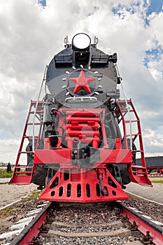 Vintage steam train on the rails close-up on blue sky background, retro vehicle, steam engine